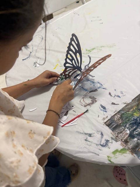 Childs hands holding a painted black and white butterfly model during an art project on a paint-covered surface